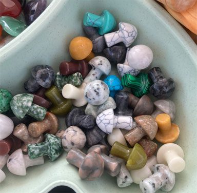 A bowl of different colored beads in the shape of hearts.