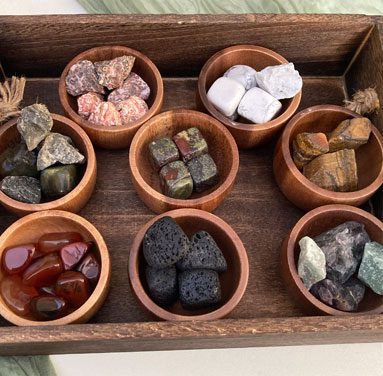 A wooden tray with bowls of different types of rocks.