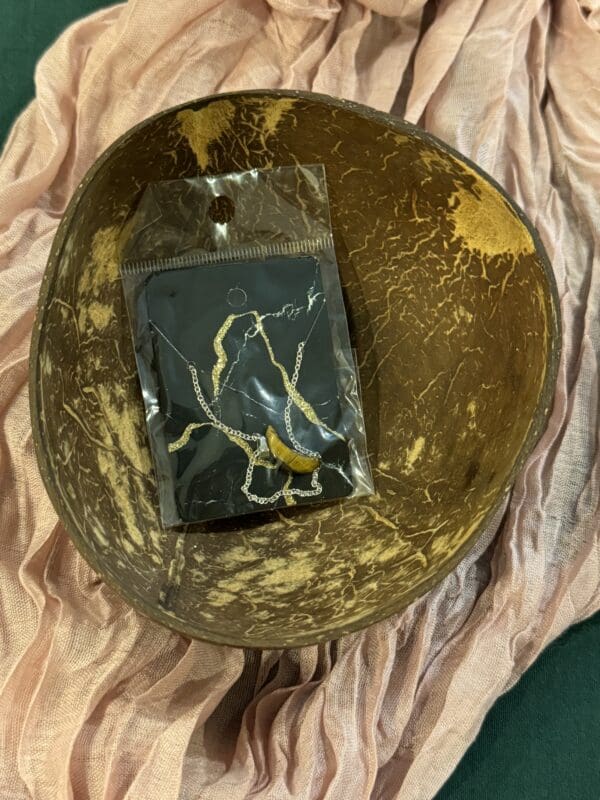 A black soap sitting in a bowl on top of a pink cloth.