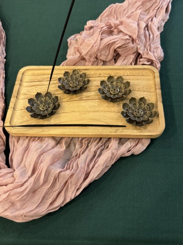 A wooden tray with four small flowers on it.