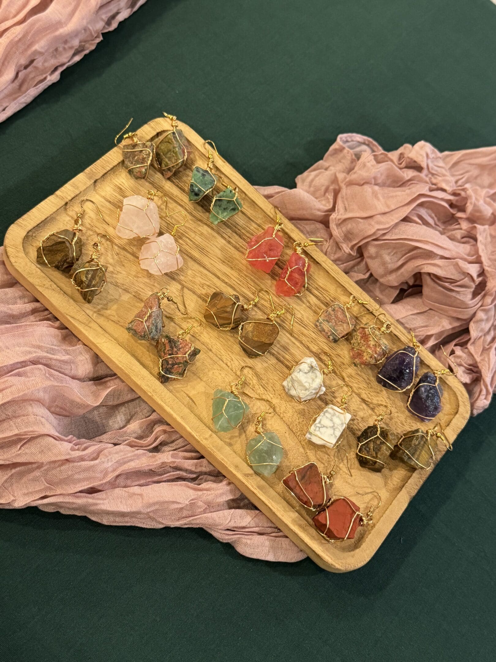 A wooden tray with many different colored stones on it.