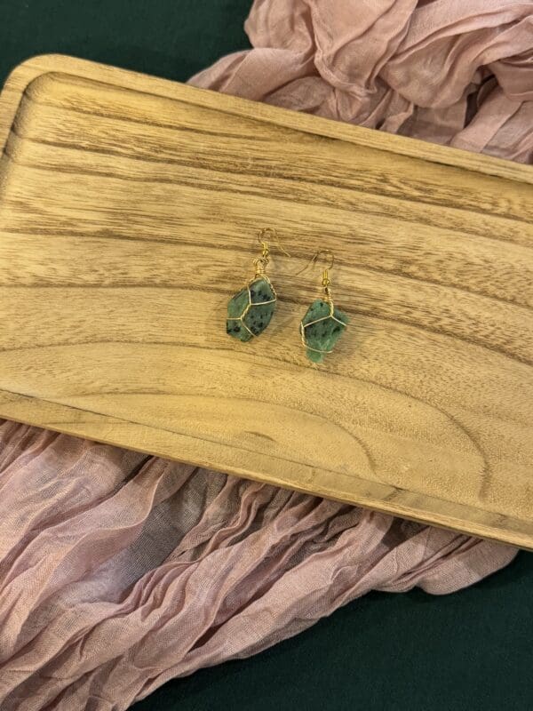 A pair of earrings sitting on top of a wooden table.