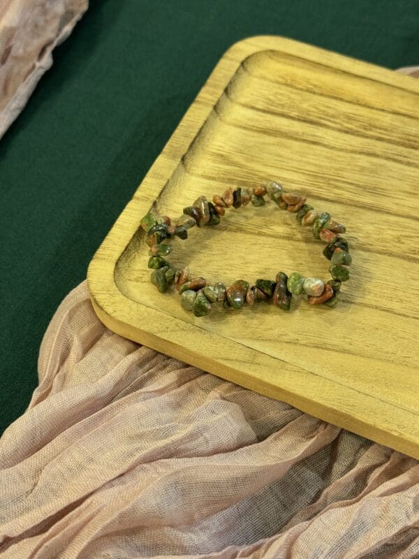 A wooden tray with some green beads on it