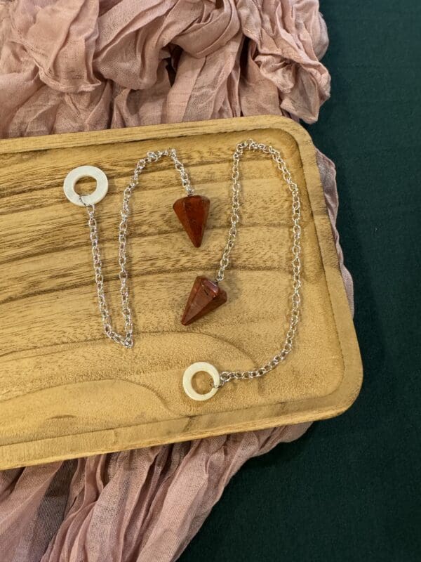 A wooden tray with two necklaces on it