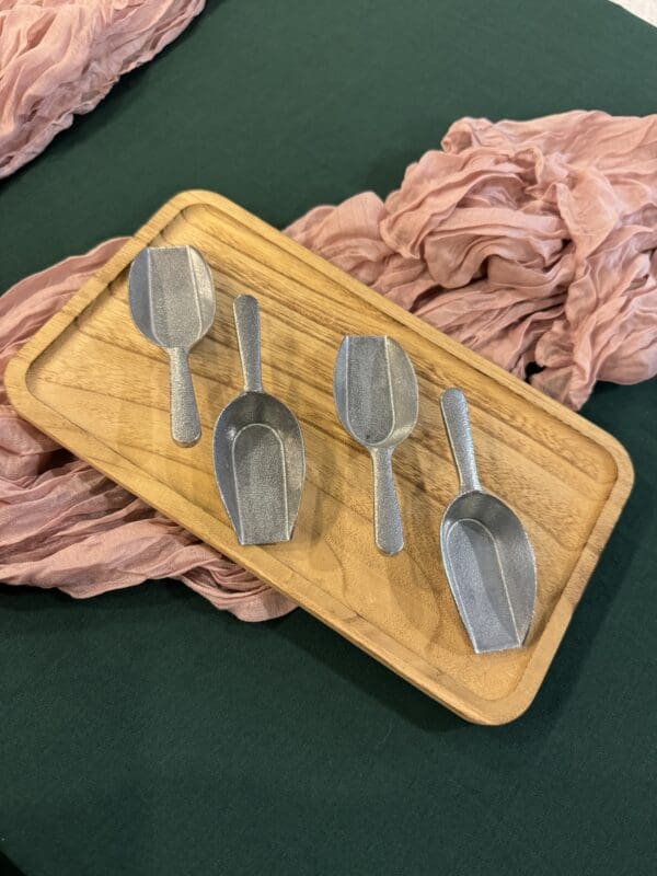 A wooden tray with four spoons on it.