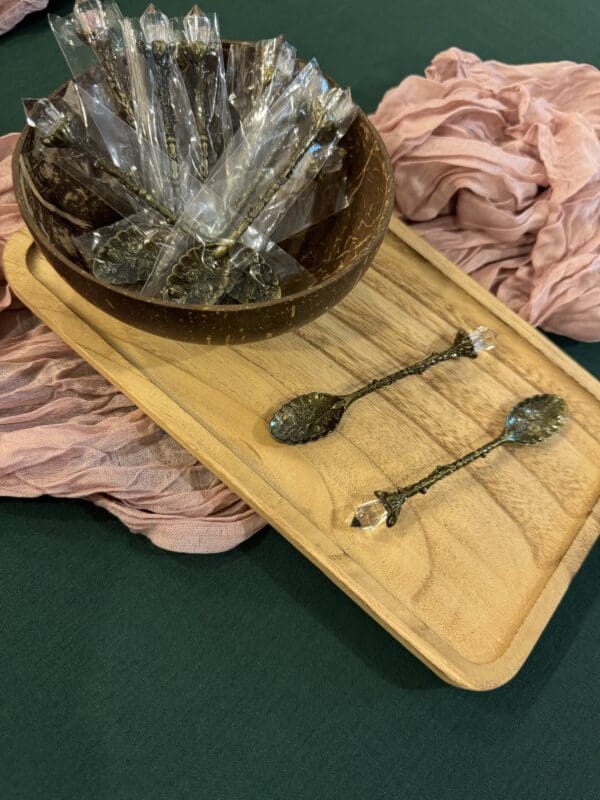 A wooden tray with two spoons and a bowl on it.