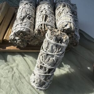 A stack of white sage bundles sitting on top of the ground.