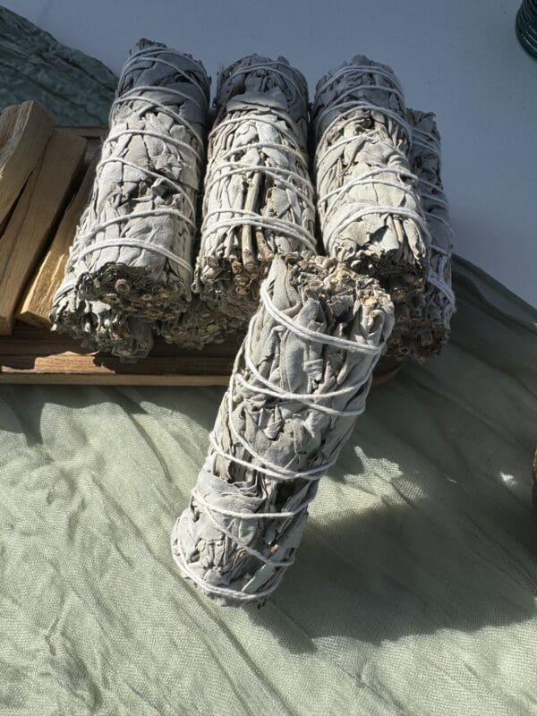 A stack of white sage bundles sitting on top of the ground.